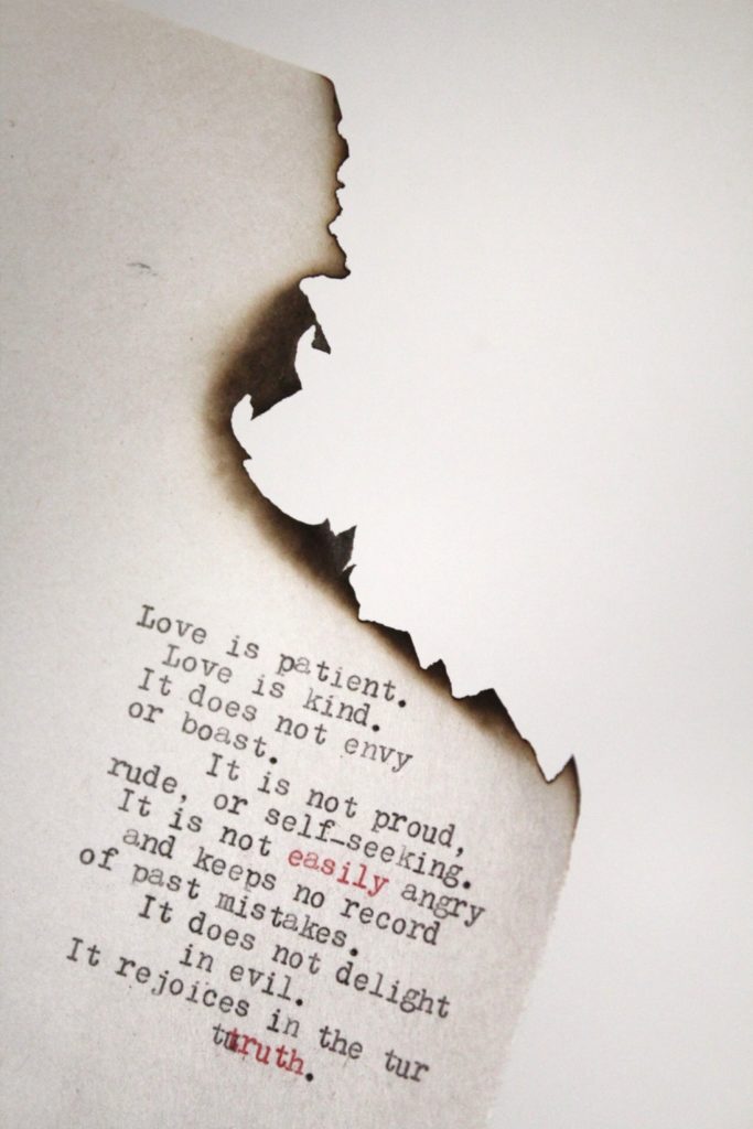 Unsplash photo by Leighann Blackwood - love is patient/love is kind, printed on burned paper - reflection of the the challenge in loving well in times of stress